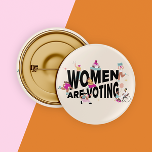 Image of cream colored safety pin style button with black design reading "Women Are Voting" with various inclusive feminine figures
